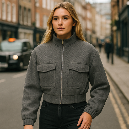 Cropped grey herringbone jacket with front zip closure, stand collar, and utility-style flap pockets.
